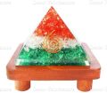 Orgone Tricolor Vastu Pyramid with Round Spring Symbol On a Brown Wooden Stand