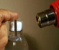 Hot Air Gun to Heat Shrink PVC Sleeves on Neck of Bottles.